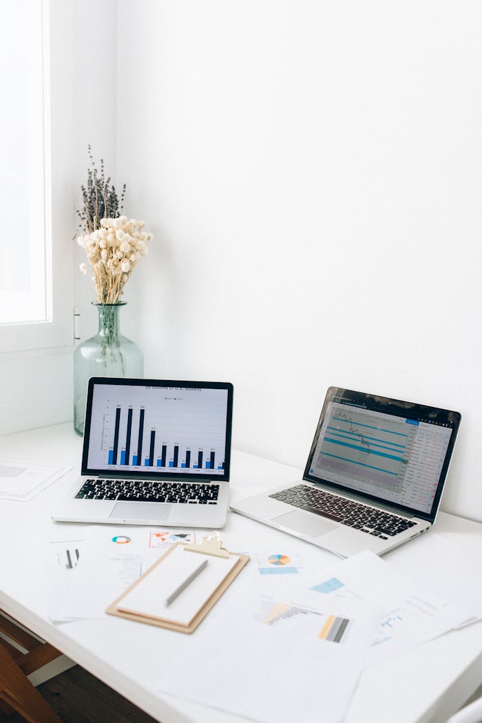 A bright office setup featuring laptops, charts, and paperwork for business analysis.